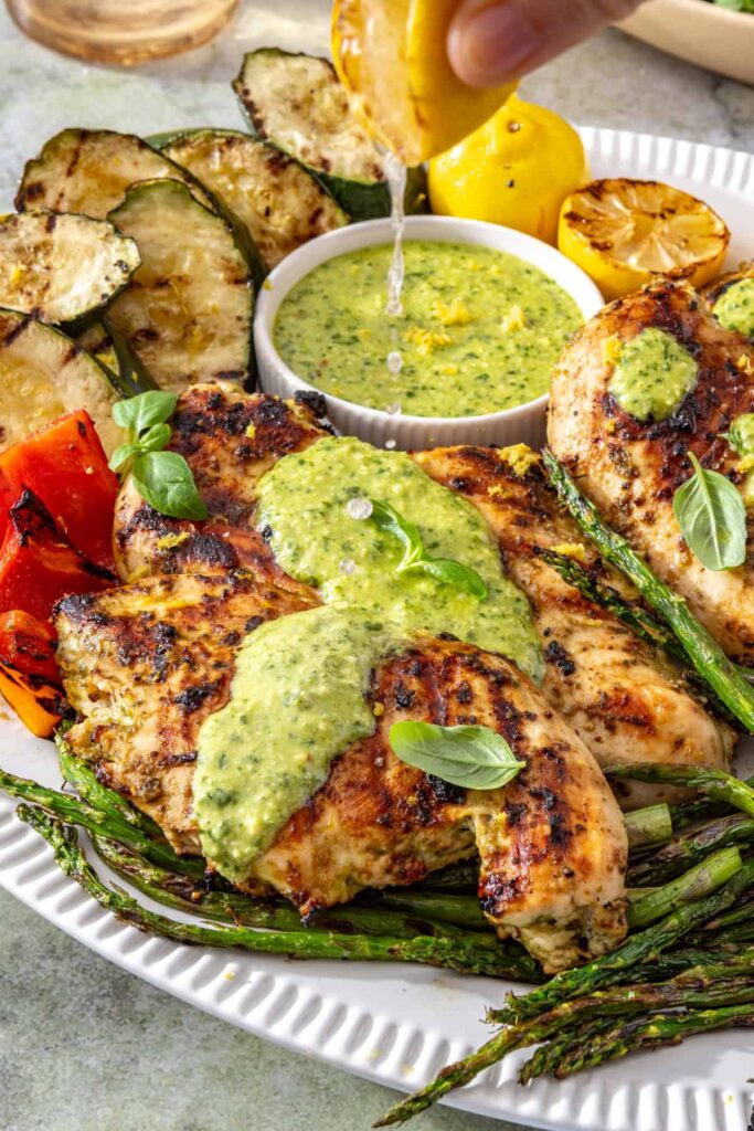 Fresh lemon juice being squeezed over lemon pesto grilled chicken