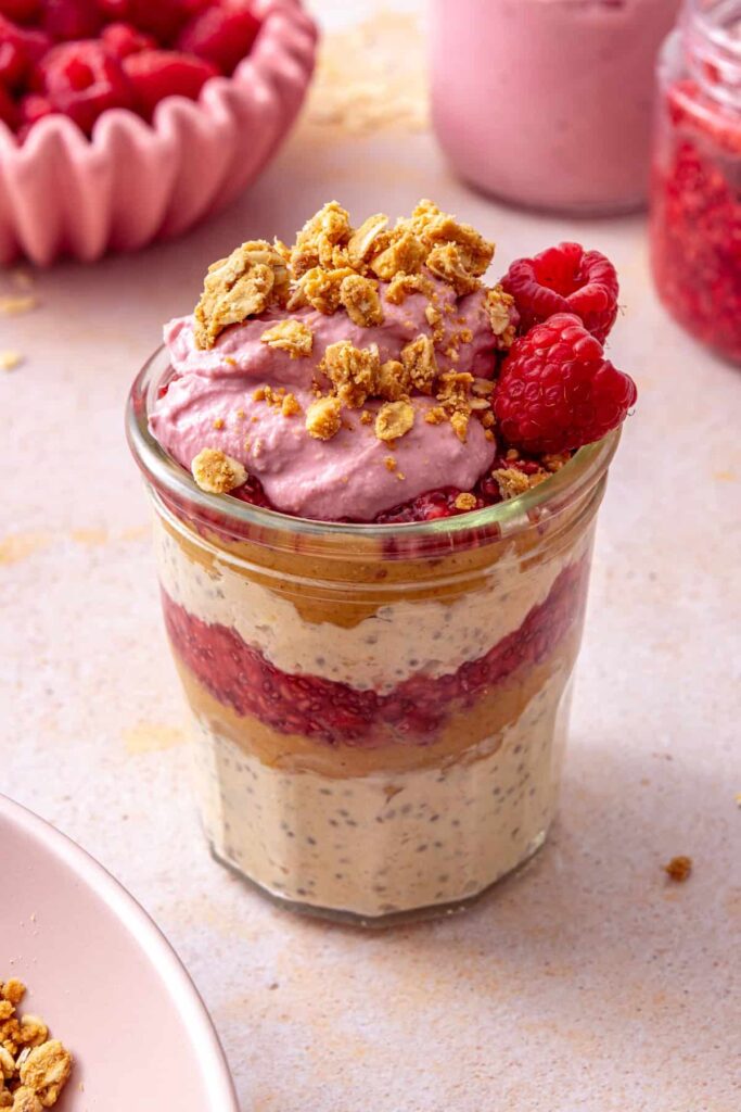 Peanut butter and jelly overnight oats topped with raspberry yogurt, peanut butter crumble, and a fresh raspberry