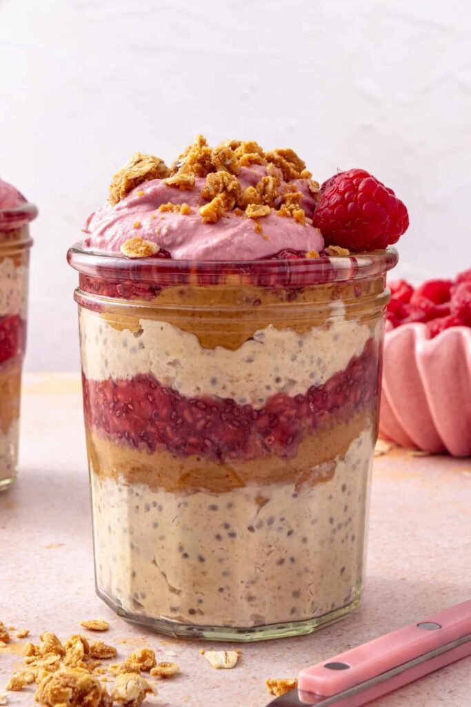 peanut butter and jelly overnight oats with a crumble topping and raspberry garnish