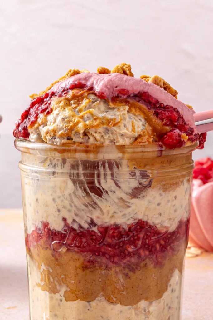 Bite of peanut butter and jelly overnight oats with raspberry yogurt topping