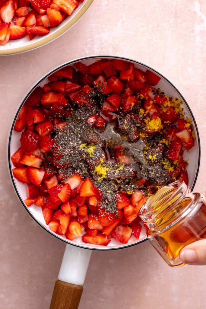 Adding ingredients into a saucepan for a strawberry jam chia filling to make oatmeal bars