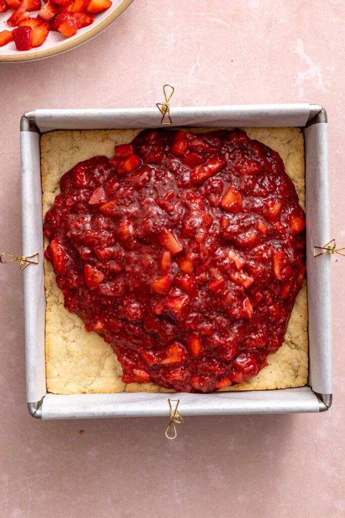 Spreading homemade strawberry chia jam over the baked crust.