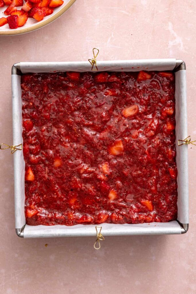Layering strawberry filling for gluten-free strawberry oatmeal bars.