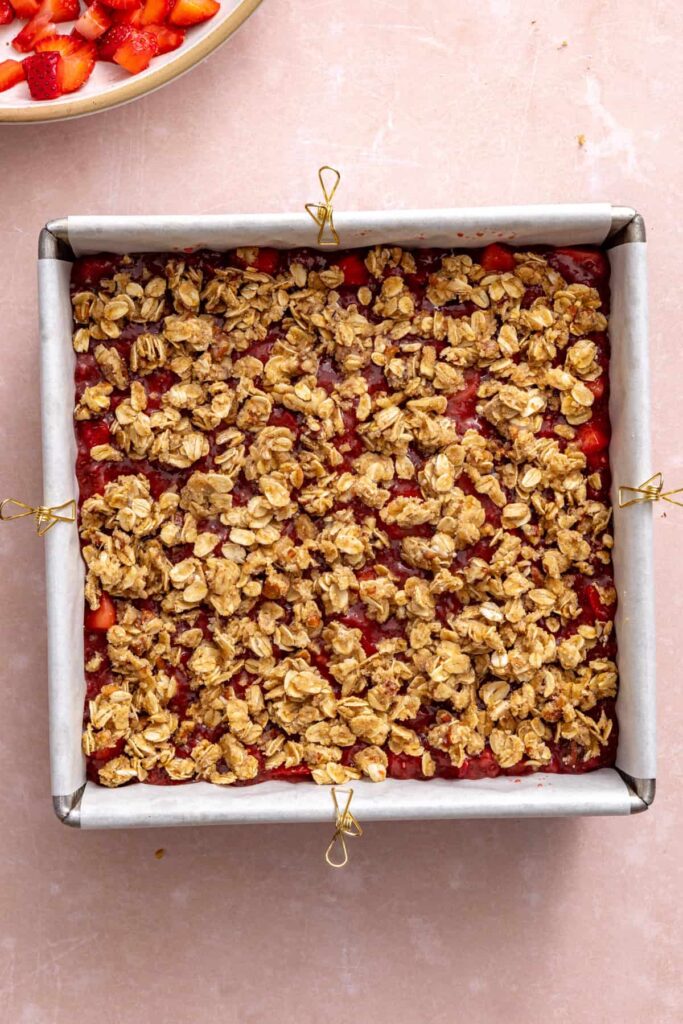 Sprinkling oat crumble over the strawberry filling before baking.