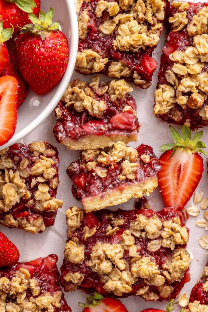 Gluten-free strawberry oatmeal bars displayed on a styled table with fresh strawberries.