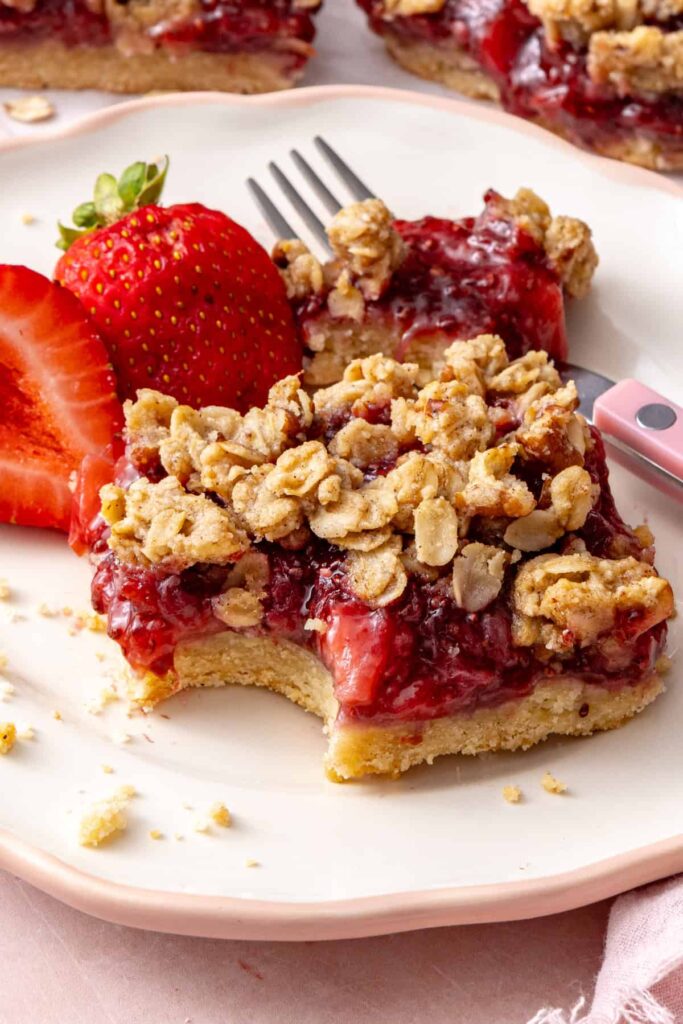 Strawberry oatmeal bar with a bite taken out, showing the soft strawberry filling and oat crumble.