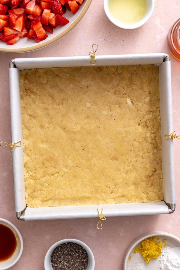 Preparing the crust layer for homemade strawberry oatmeal bars.