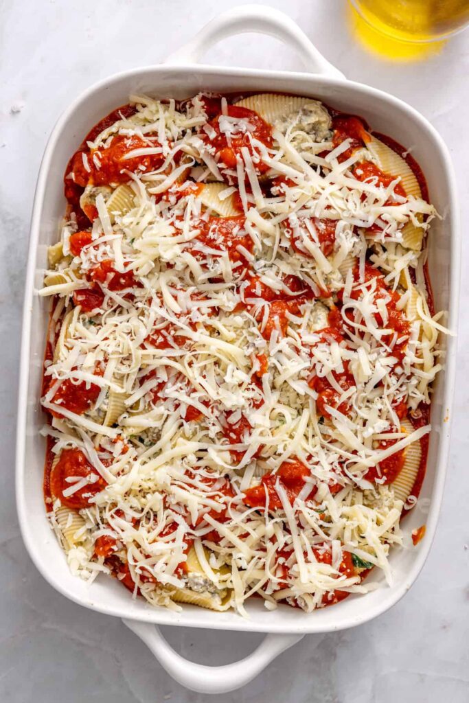 Layered stuffed shells covered in marinara and cheese ready to bake