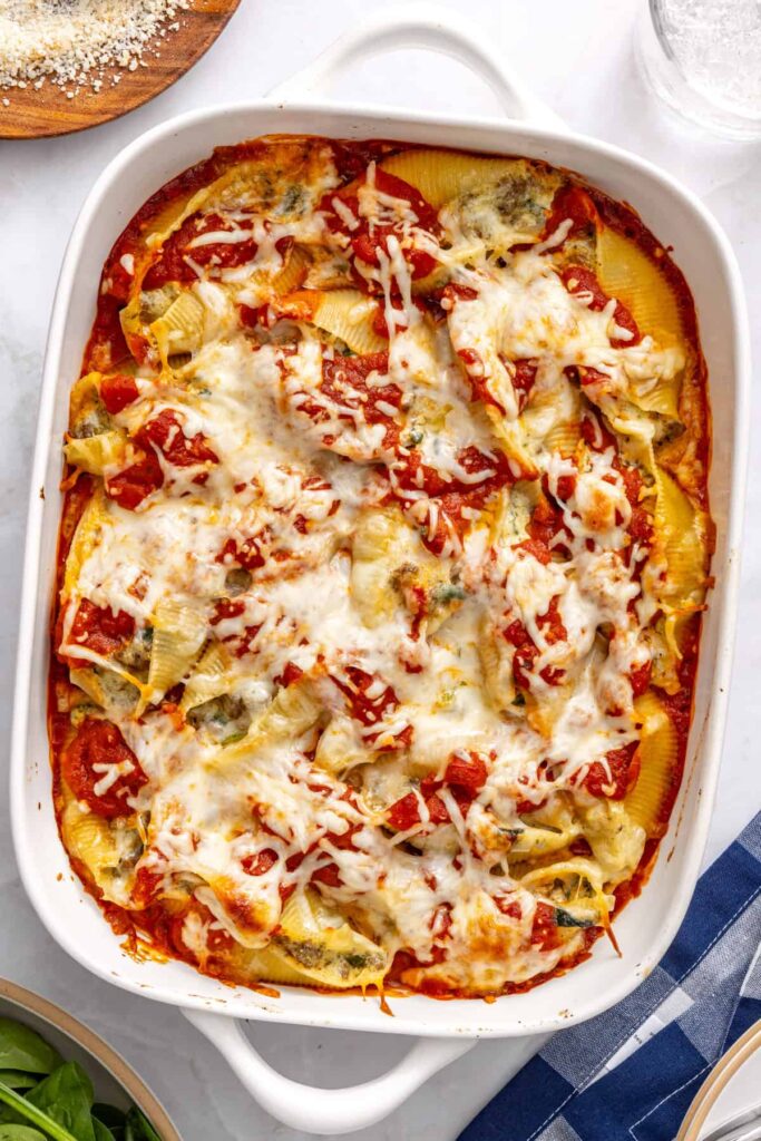 Freshly baked stuffed shells resting in baking dish after oven before garnishing with basil and olive oil