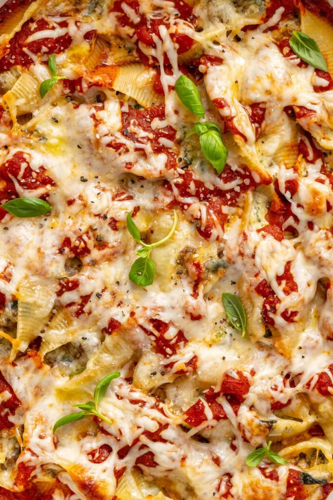 Zoomed-in view of pesto beef stuffed shells highlighting cheesy baked layers and marinara sauce