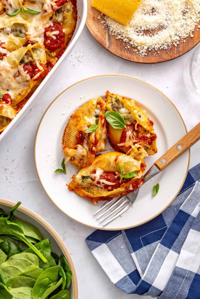 Stuffed shells served on plate with fork and grated parmesan on styled table setting