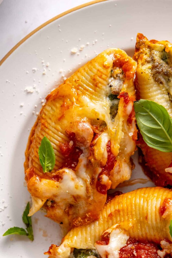 Close overhead view of stuffed shells on plate with fork and melted cheese detail