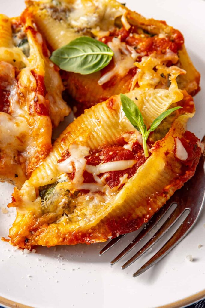 Detailed plated shot of stuffed shells highlighting texture of ricotta and beef filling