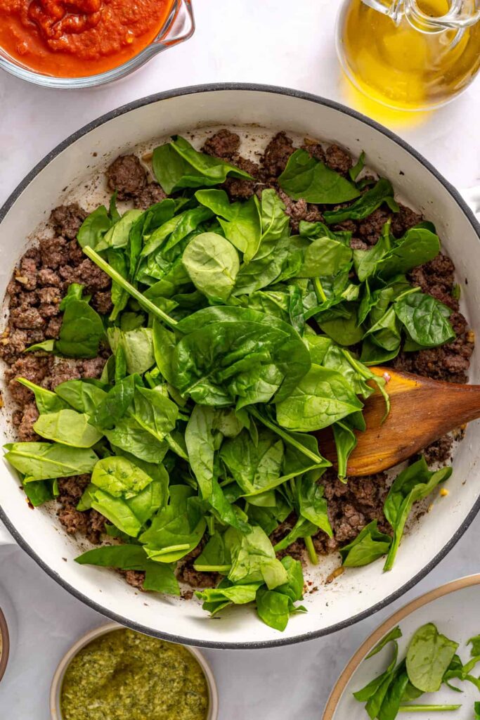 Fresh spinach wilting into cooked ground beef mixture for stuffed shells filling