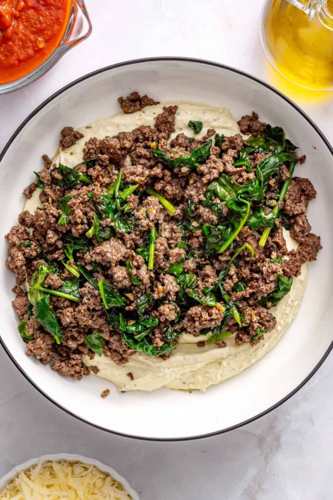 Beef mixture being combined with creamy ricotta base for pesto stuffed shells