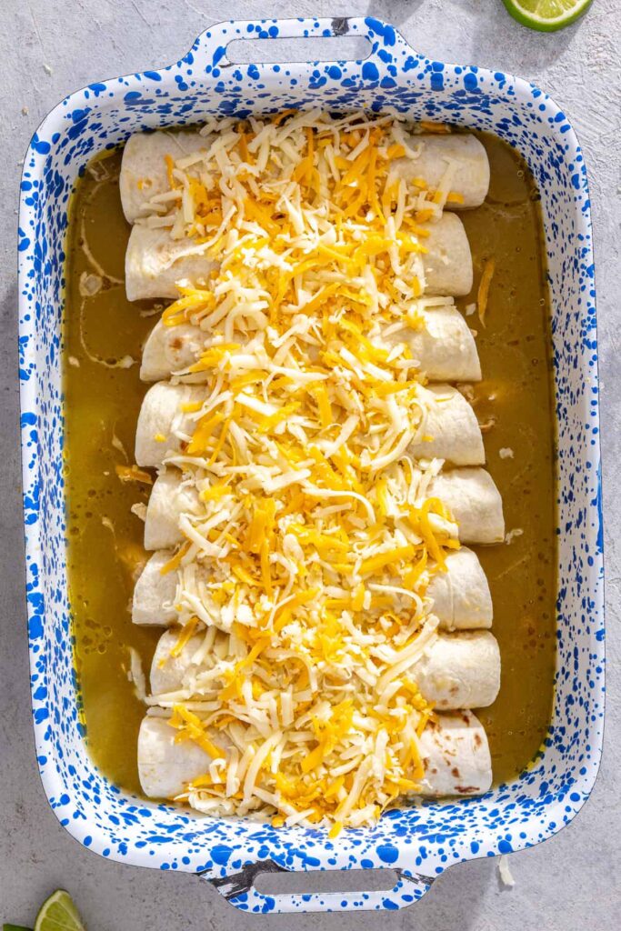 Chicken enchiladas topped with Monterey Jack and cheddar cheese before baking
