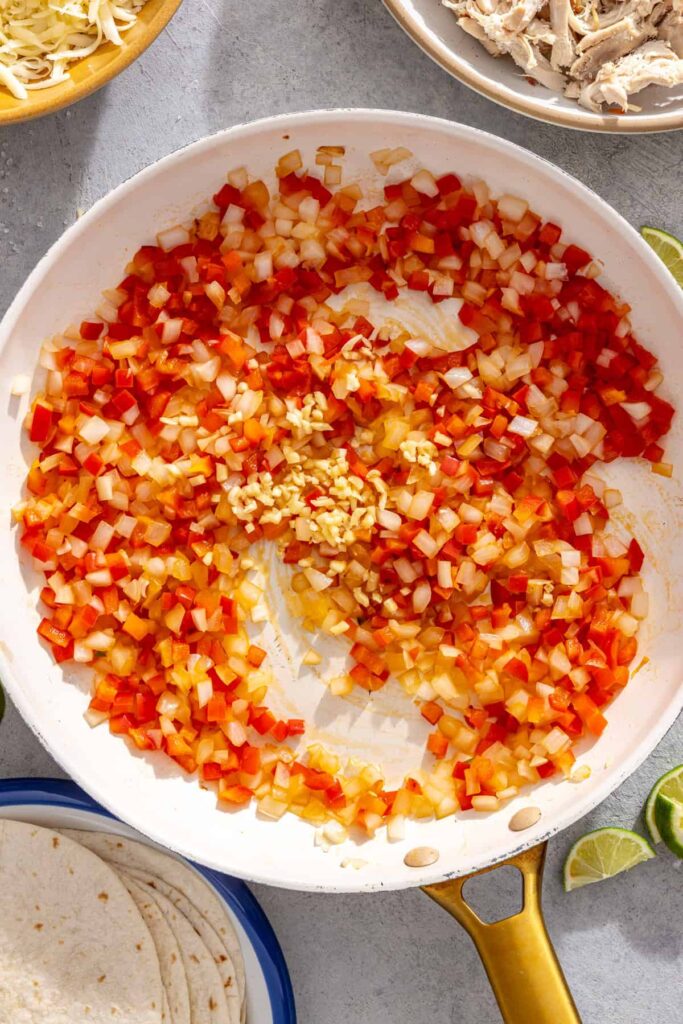 Onion, bell pepper, and garlic sautéing in a skillet