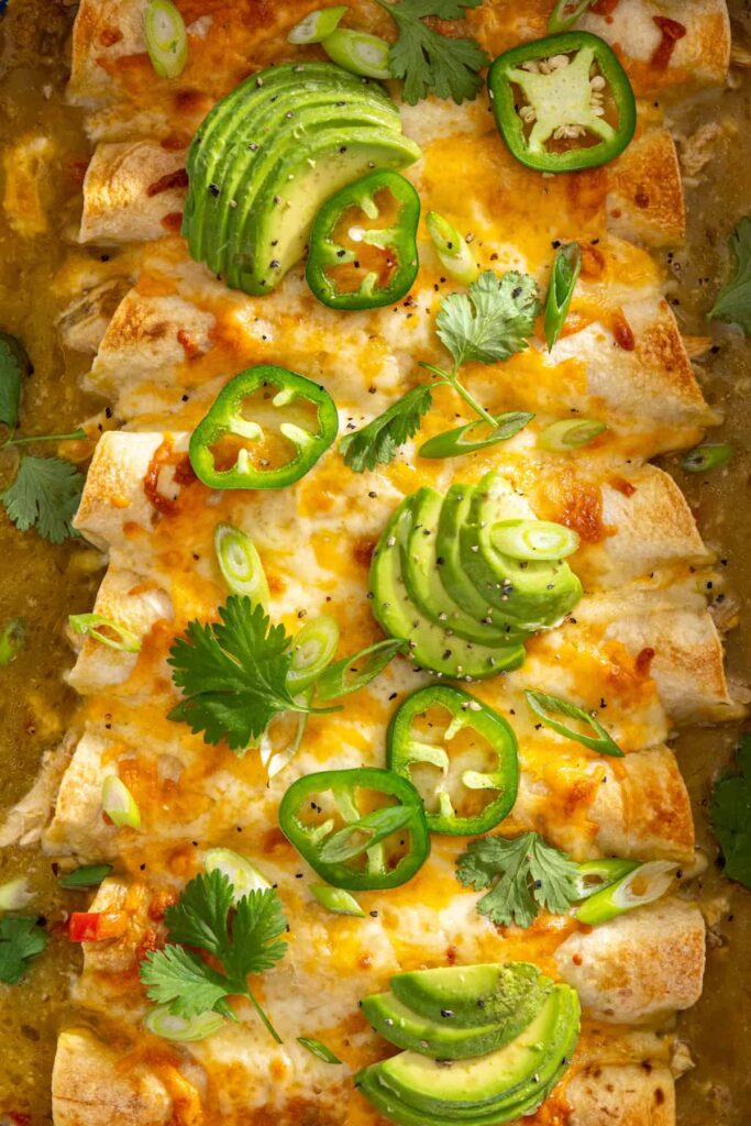Close-up of creamy green chicken enchiladas with melted cheese and salsa verde