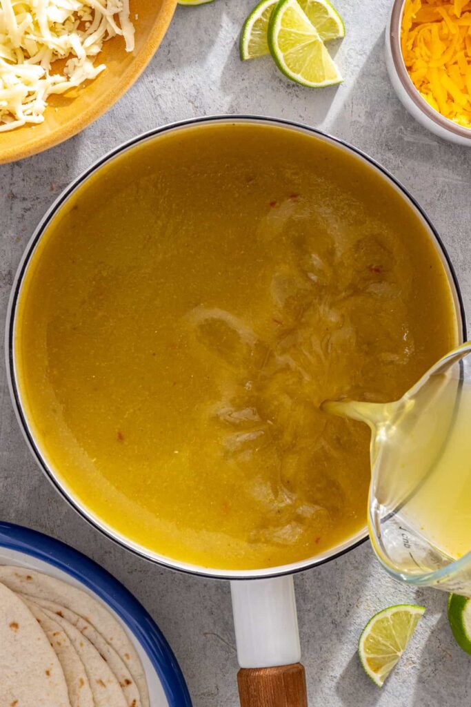 Green enchilada sauce and chicken broth warming together in a saucepan