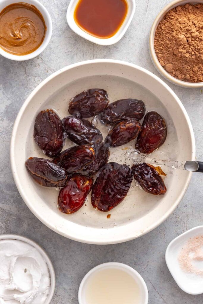 pouring hot water over Medjool dates in a bowl for a healthy date frosting recipe