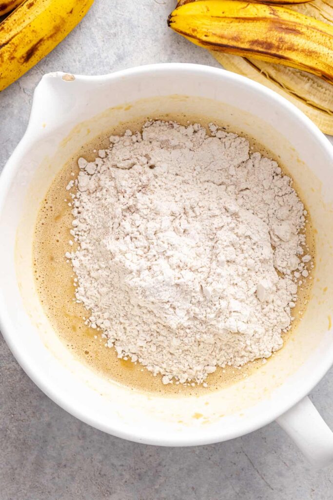 adding dry ingredients to wet ingredients for gluten-free vanilla banana birthday cake