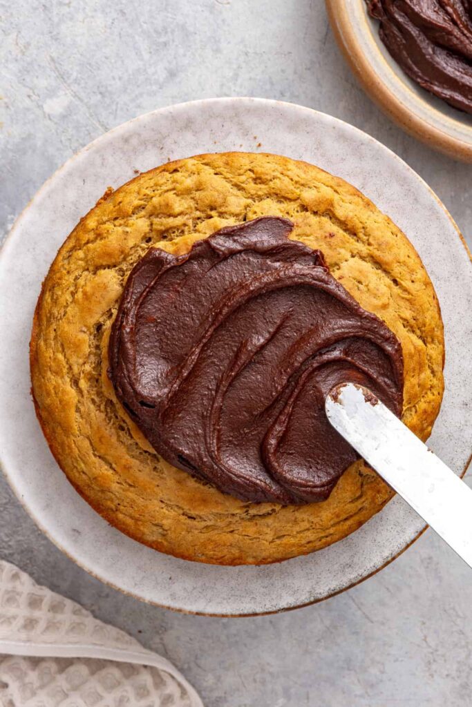 Spreading healthy chocolate date frosting over healthy banana birthday cake