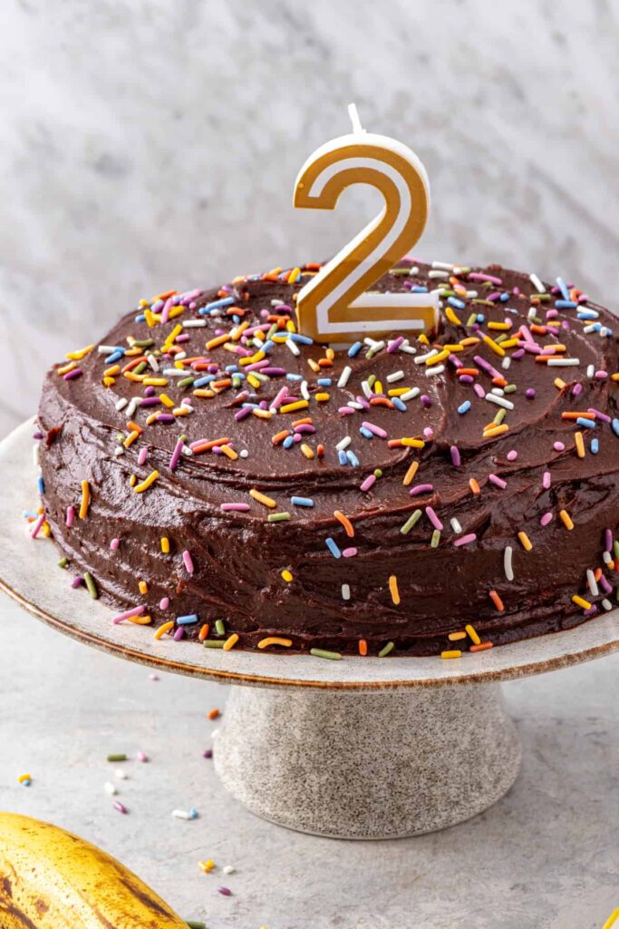 Healthy banana birthday cake with rainbow sprinkles and number two birthday candle