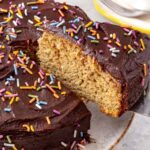Healthy banana birthday cake with chocolate date frosting and rainbow sprinkles showing soft fluffy texture