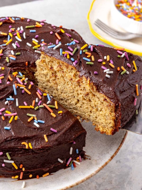 Healthy banana birthday cake with chocolate date frosting and rainbow sprinkles showing soft fluffy texture