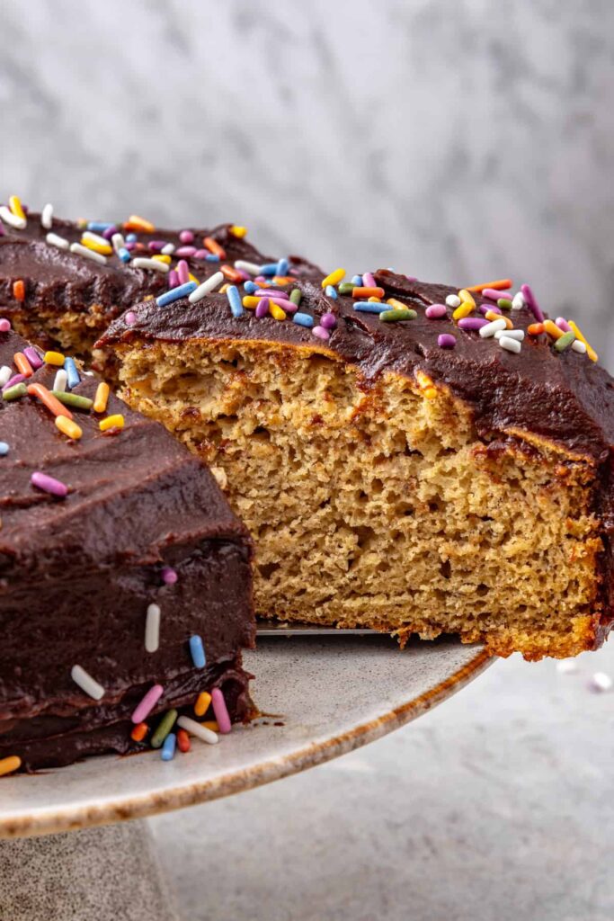 Healthy banana birthday cake slice lifted from cake stand