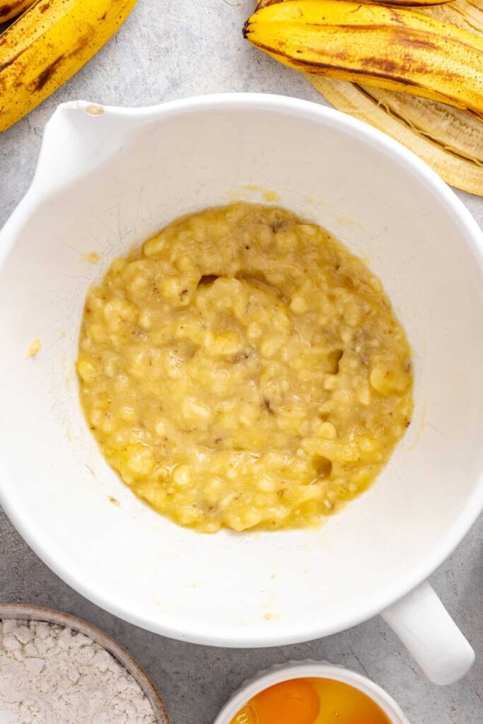 mashed bananas in a bowl, ready to be mixed with ingredients for a vanilla banana birthday cake for kids