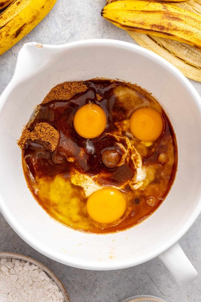 mashed bananas, eggs, vanilla extract, and Greek yogurt in a mixing bowl for banana birthday cake