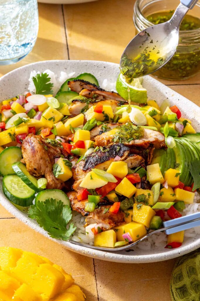 Fresh cilantro-lime drizzle poured over honey lime grilled chicken with mango salsa