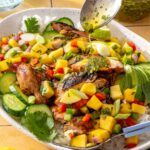 Honey lime grilled chicken with fresh mango salsa and cilantro-lime drizzle served on a platter with avocado and lime wedges