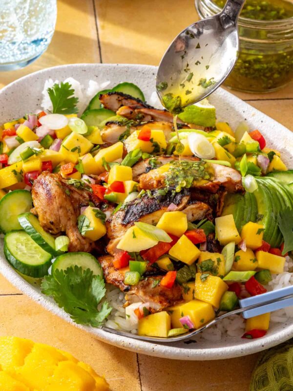 Honey lime grilled chicken with fresh mango salsa and cilantro-lime drizzle served on a platter with avocado and lime wedges