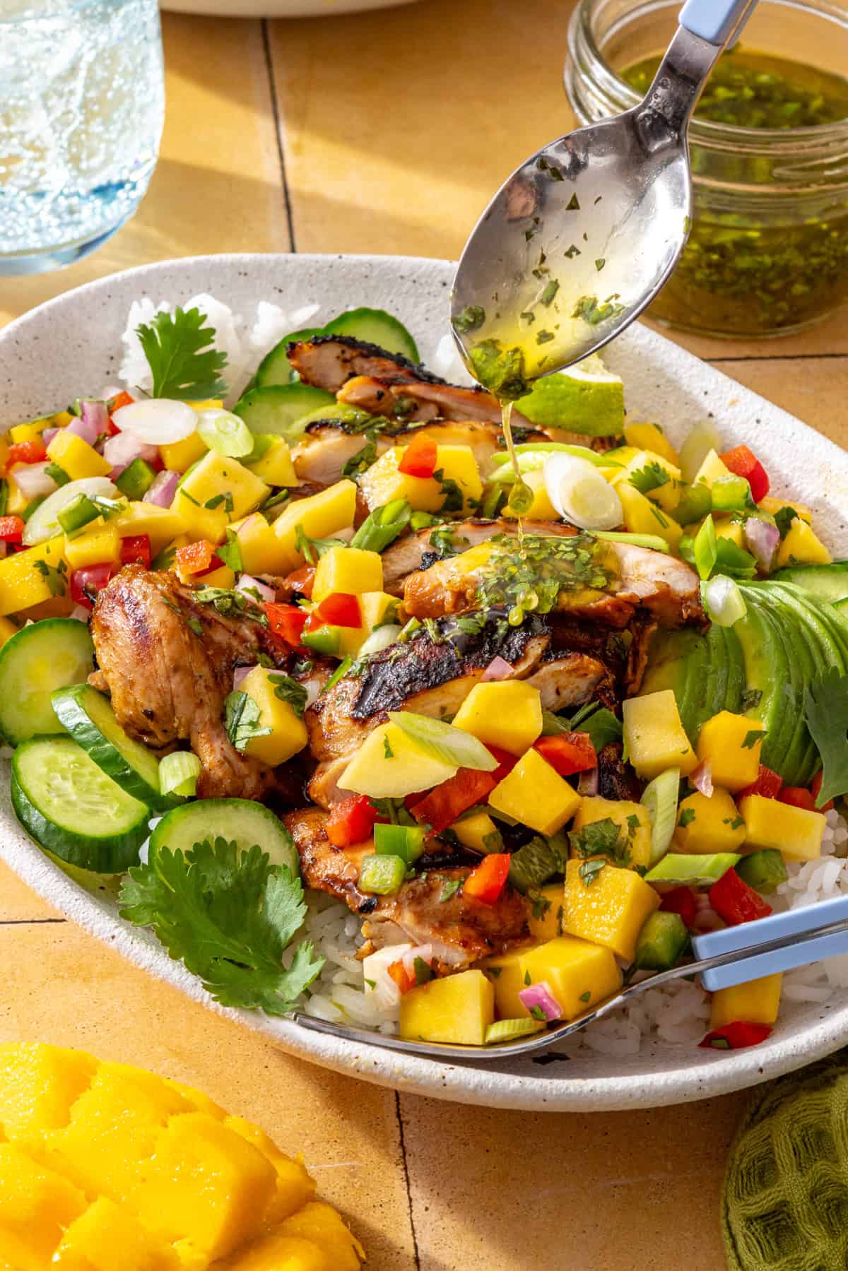 Honey lime grilled chicken with fresh mango salsa and cilantro-lime drizzle served on a platter with avocado and lime wedges