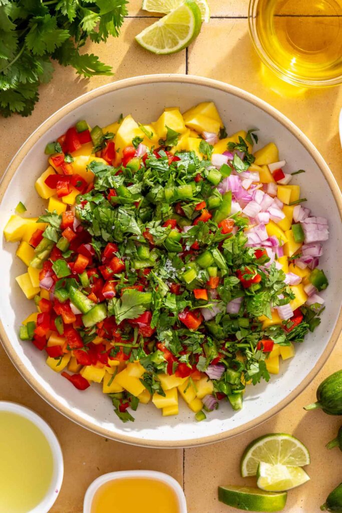 Mixing fresh mango salsa for honey lime grilled chicken