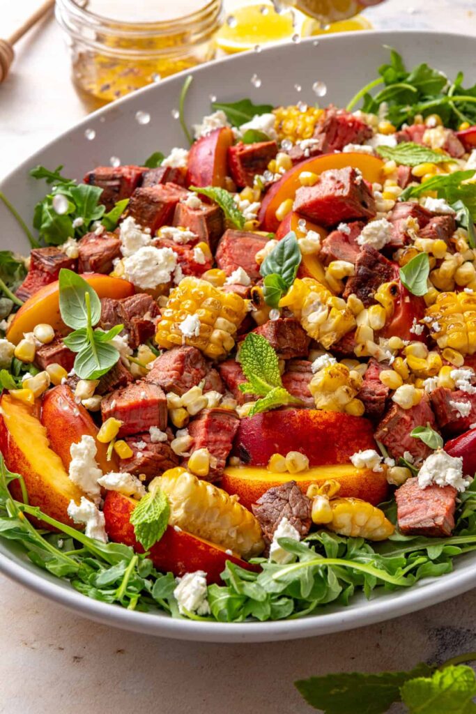 Adding fresh lemon juice to summer steak salad with grilled ingredients