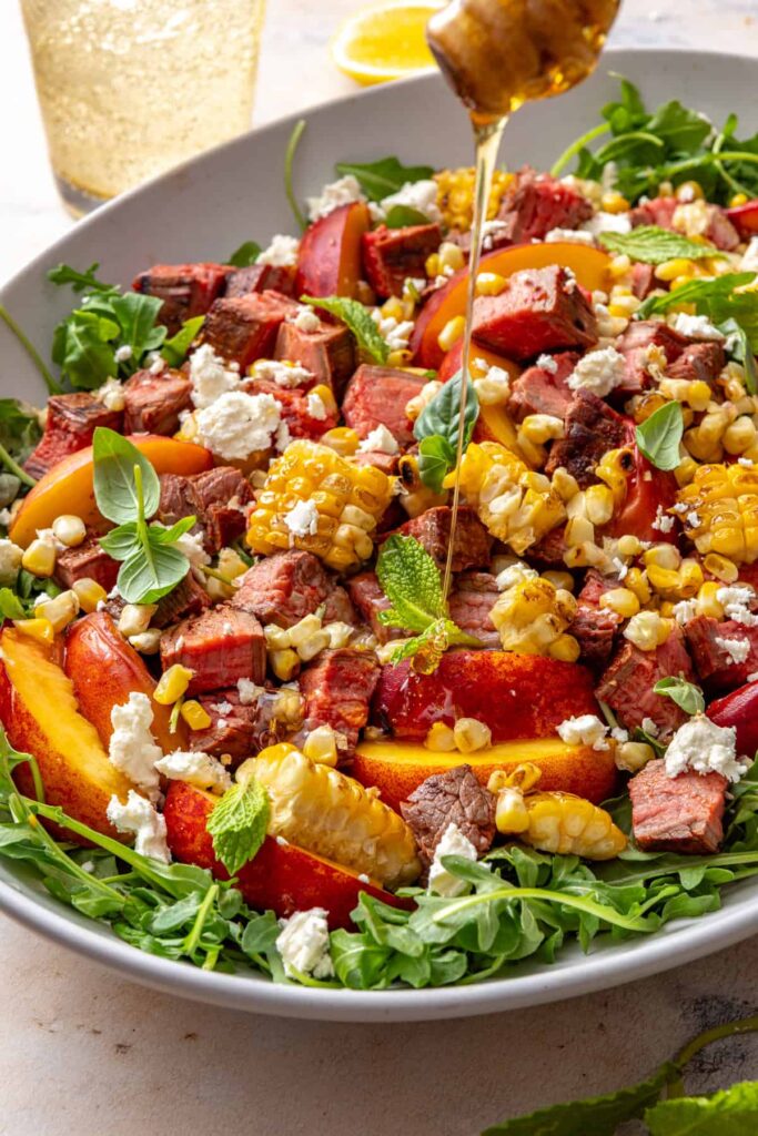 Finishing grilled steak salad with spicy honey drizzle