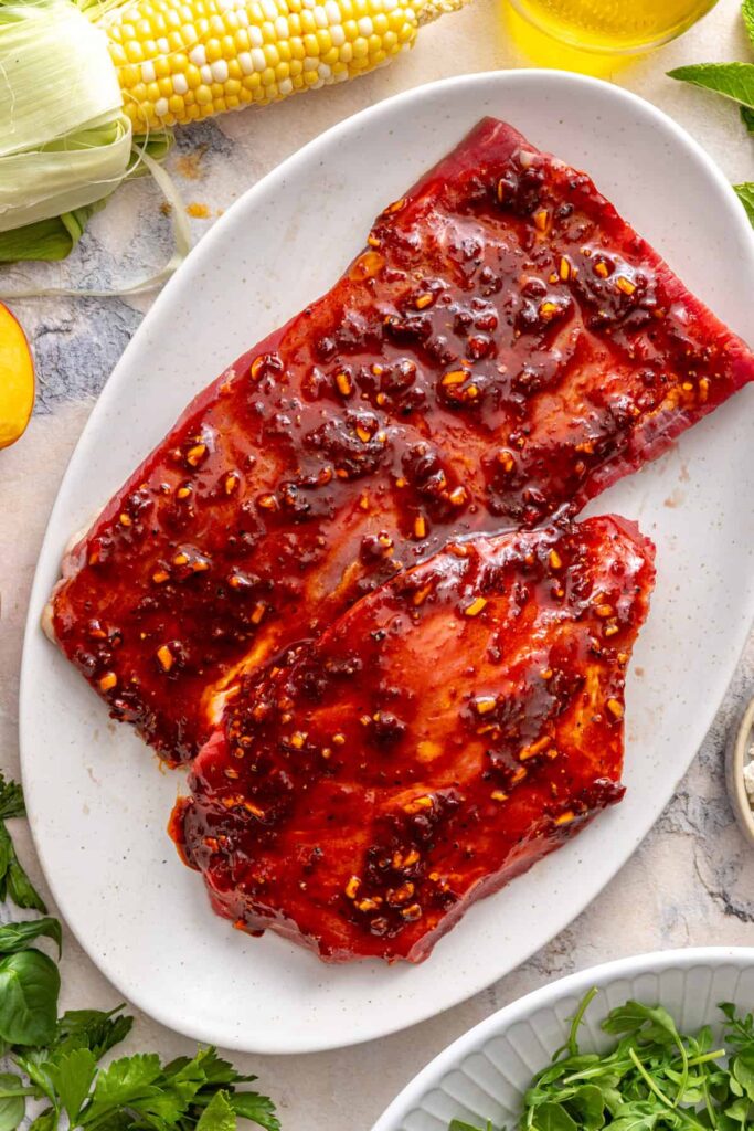 Flank steak coated in spicy harissa marinade before grilling