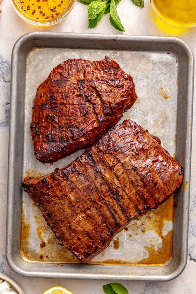Grilled flank steak resting before slicing for harissa steak salad