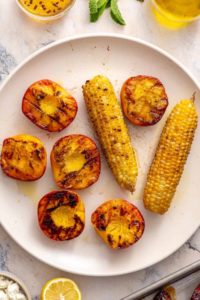 Sliced grilled peaches and charred corn prepared for steak salad