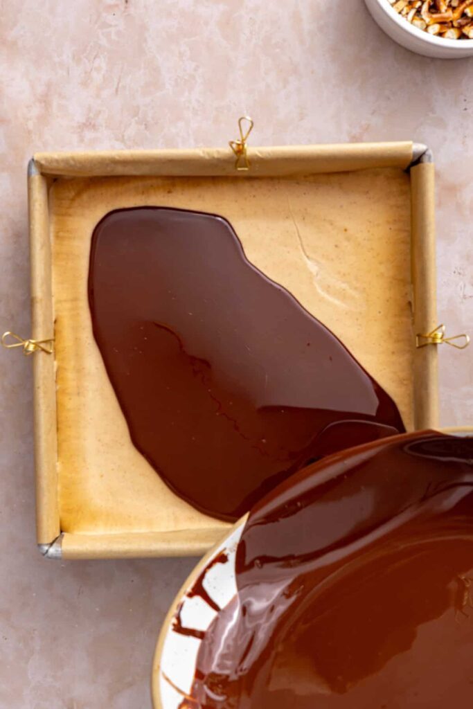 Pouring melted dark chocolate over the frozen peanut butter filling.