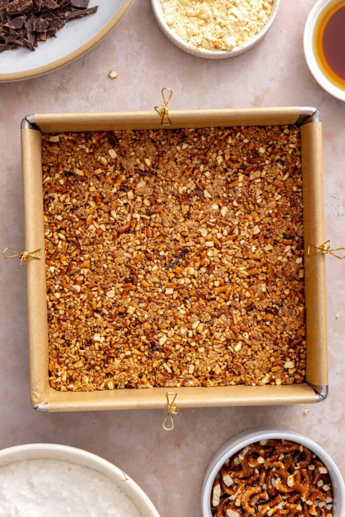 Pretzel crust packed evenly into the pan for frozen peanut butter pretzel bars.