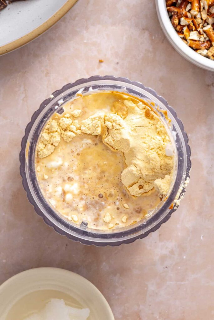 Blending cottage cheese, peanut butter, vanilla protein powder, and maple syrup until smooth.