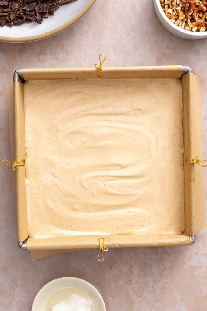 8x8 baking pan lined with parchment paper for frozen peanut butter pretzel bars.