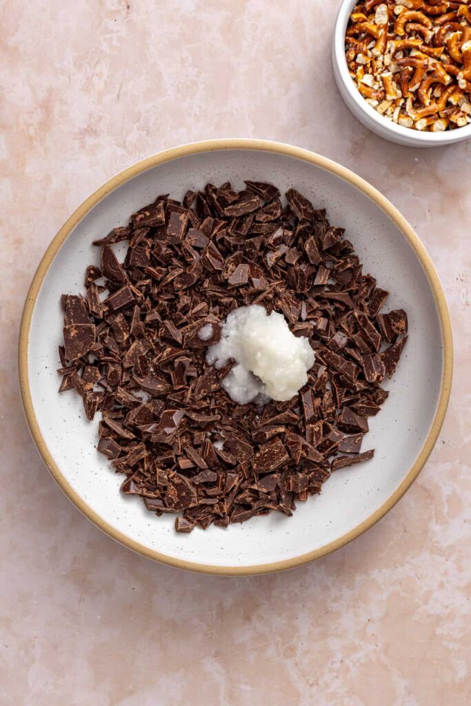 chopped dark chocolate and coconut oil in a bowl, ready to be melted for frozen peanut butter pretzel bars