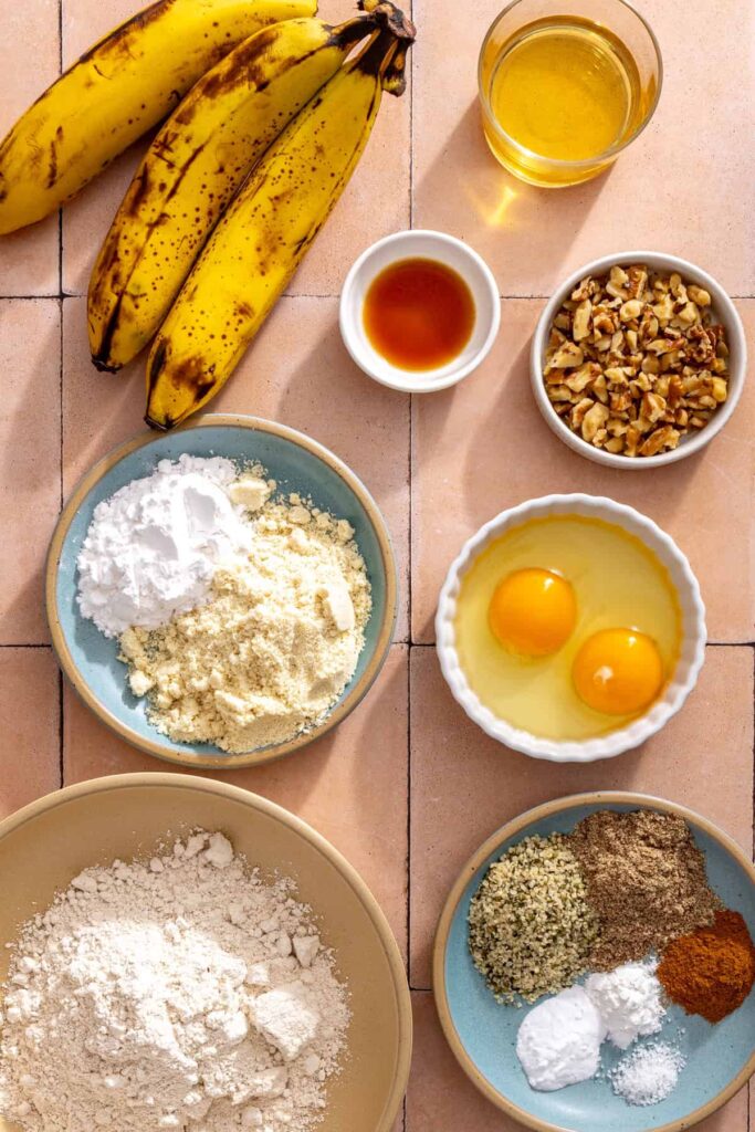 Ingredients for toddler banana muffins including ripe bananas, oat flour, almond flour, flaxseed, hemp seeds, eggs, and walnuts