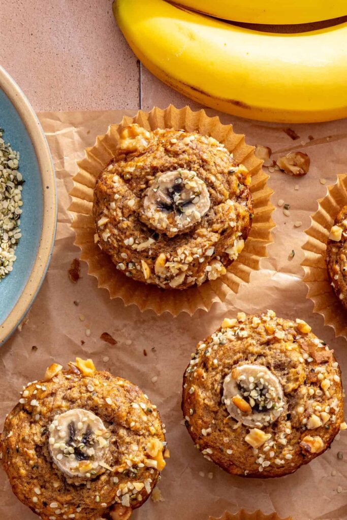 Single no added sugar banana muffin surrounded by freshly baked muffins