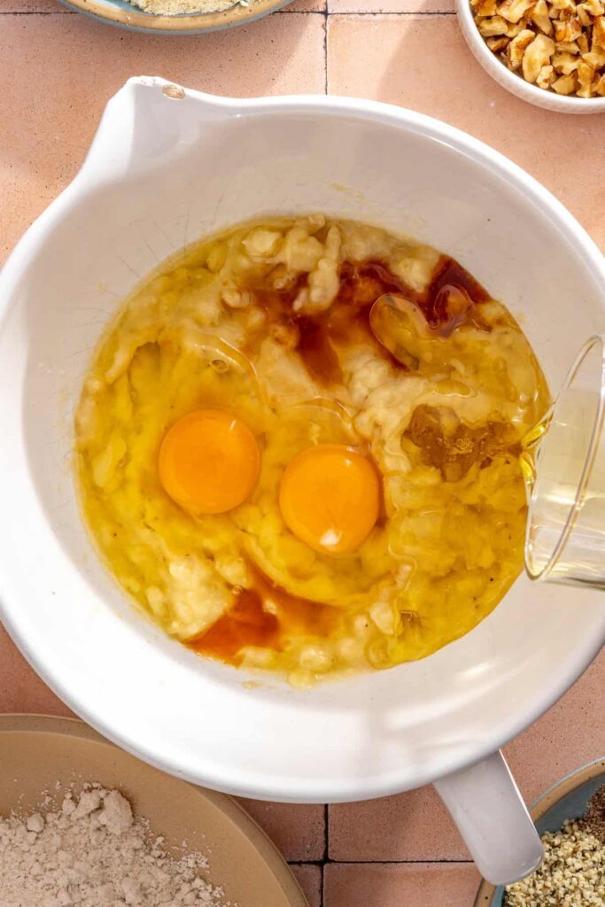 Eggs, avocado oil, vanilla, and mashed bananas mixed together for toddler banana muffins
